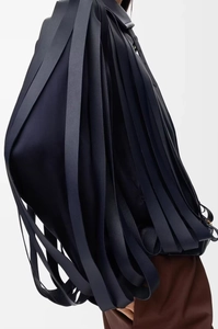 Detail shot of a dark navy leather tote bag with long cascading tassels and metal buckles