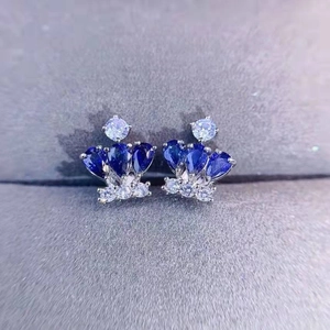 Macro detail of crown earrings featuring blue pear-shaped stones in fine claw setting