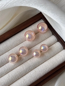Macro shot of pink mermaid pearl earrings arranged in a luxury wooden jewelry box
