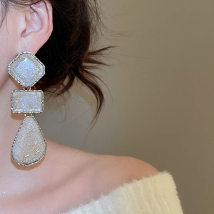 Detailed close-up of resin drop earrings with white marble texture and gold foil flakes
