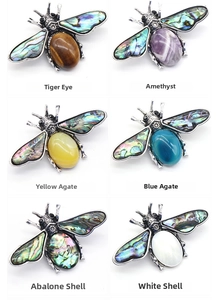 Macro detail of bee brooches with abalone shell wings and various gemstone cabochons