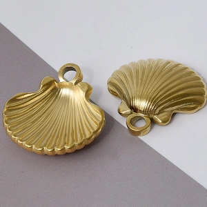 Detailed view of two gold shell charms with rings for jewelry making and necklaces
