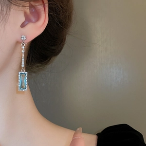 Detail of silver drop earring with blue rectangular stone and sparkling zircons