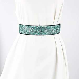 Detail of emerald and silver rhinestone elastic waist belt on a white dress
