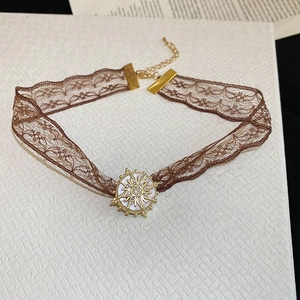 Detail of vintage brown lace choker with gold sun pendant and mother of pearl inlay