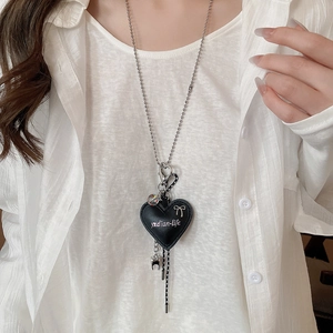 Detail of a black heart PU pendant with a silver ball chain on a white shirt
