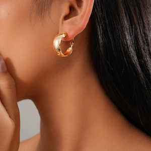 Close-up of elegant gold C-shaped twisted metal hoop earrings worn by a model