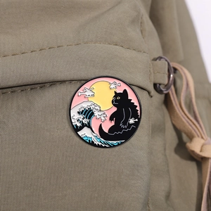 Detail of Catzilla enamel pin with Great Wave design on a khaki canvas backpack