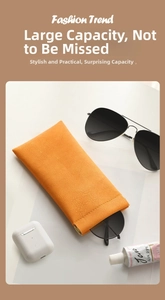 Detail of orange lychee textured leather eyewear pouch with automatic closing metal clip
