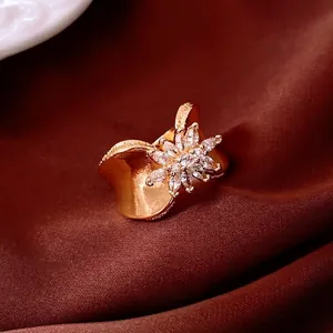 Gold-plated flower ring with white zircon petals and wavy wide band on brown velvet