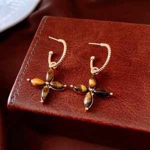 Gros plan sur des boucles d'oreilles fleur en or 18 carats avec pierres œil de tigre