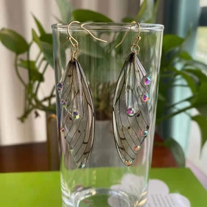 Elegant S925 silver cicada wing drop earrings with crystals on a glass cup