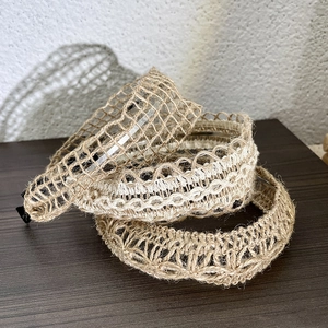 Three woven linen headbands in beige and brown displayed on a vintage wood surface