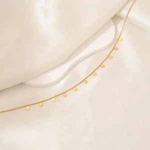 Detail view of golden stainless steel necklace with small four-petal flower charms on silk