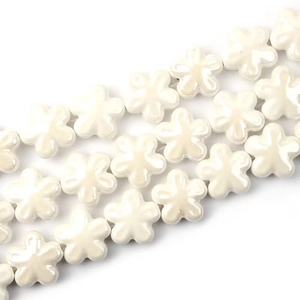 Vista macro di perle di ceramica a fiori bianchi per gioielli fatti a mano e accessori fai-da-te