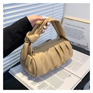 Detail of khaki pleated cloud bag showing the soft knotted handle and smooth gold zipper