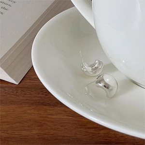 Orecchini a perno curvi in argento minimalisti su un piatto di ceramica bianca elegante