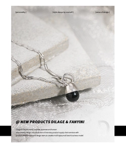 Detail view of S925 silver necklace with black agate sphere on a textured background