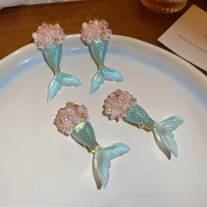 Close-up of pink beaded flower and light blue mermaid tail hair clips on a white plate