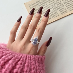 Close-up of a pear-shaped violet zircon ring with silver band worn on a hand
