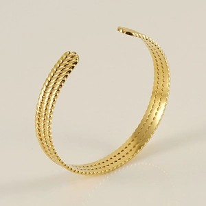 Détail de la texture tressée dorée sur un bracelet jonc réglable en acier inoxydable