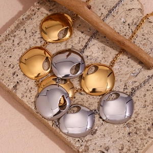 Detailed view of 18K gold plated teardrop cut-out circular pendants on textured stone
