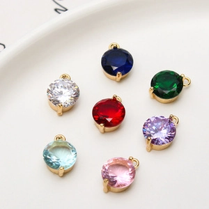 Detailed view of colorful round zirconia charms for DIY jewelry making on white ceramic tray