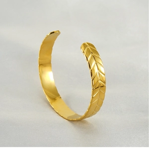 Detailed close-up of 18k gold plated wheat ear pattern on adjustable steel cuff bracelet