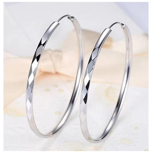 Close-up of silver hoop earrings featuring diamond-cut geometric texture on velvet