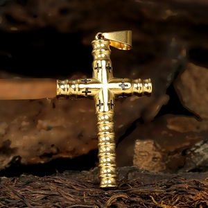 Detailed macro view of a gold cylindrical cross pendant with intricate black carvings