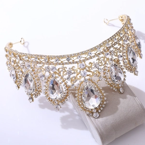 Detailed close-up of golden bridal crown with teardrop crystals on gray velvet pad