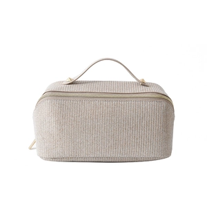 Large beige woven cosmetic bag with golden zipper and handle on a white background