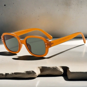 Close-up of amber oval sunglasses SN3812 with grey lenses on concrete stone texture