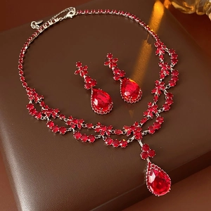 Macro detail of red zircon flower teardrop necklace and earrings set on leather
