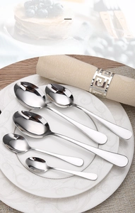 Set of five polished stainless steel pointed spoons in various sizes on a dinner plate
