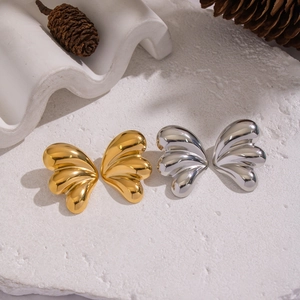 Polished butterfly wing earrings in gold and silver finish on stone pedestal