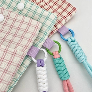 Detail of plaid fabric pouches with thick braided lanyards in various pastel colors