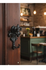 Detailed close-up of a vintage black cast iron fleur-de-lis hook on dark wood