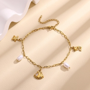 Detailed macro of gold titanium steel anklet with shell, starfish and baroque pearl charms