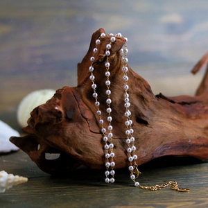 Elegant French style pearl necklace with K18 gold chain displayed on rustic wood