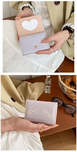 Detail of faux pearl bow wallet with heart-shaped window and snap closure