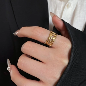 Detail of golden olive leaf ring on model with professional minimalist suit background