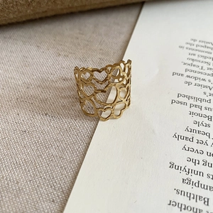 Detailed view of a gold open ring with hollow heart patterns on a vintage book page