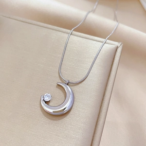 Detailed shot of crescent moon pendant with round zircon on sleek snake chain