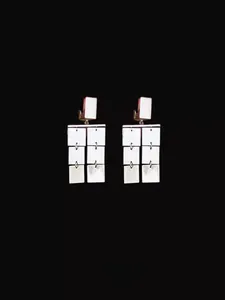Detail view of silver geometric sheet tassel earrings with multi-layer metal segments