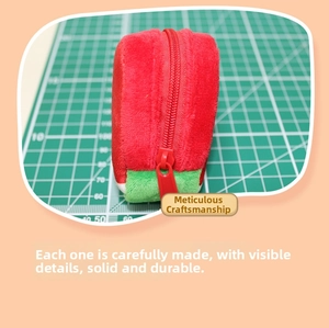 Detail shot of strawberry plush coin purse showing the red zipper and soft texture
