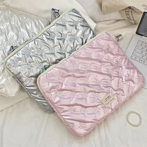 Detailed view of satin quilted laptop sleeves with bow patterns in white, silver, and pink