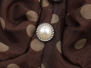 Macro shot of pearl button with silver twisted edge on polka dot organza midi dress
