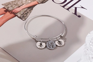 Detail view of silver adjustable bangle with boy, girl, and LOVE heart pendants