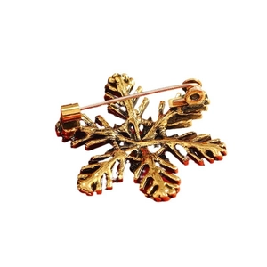 Back view of a gold Christmas snowflake brooch showing the secure safety pin clasp detail